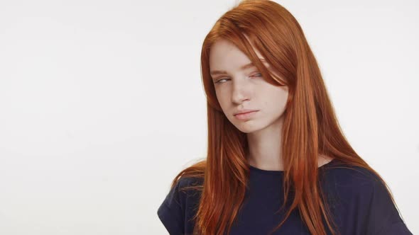 Outraged Redhaired Caucasian Teenage Girl Standing on White Background Looking at Camera and Away in