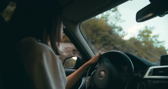 Woman Drive Car on Road Trip Smiling and Speak with Passenger on Rear Seat