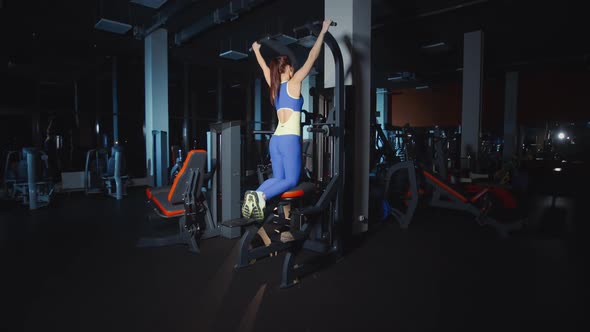 Woman Doing Pull Ups Training Hands and Shoulders on Weights Lifting Machine Work Out