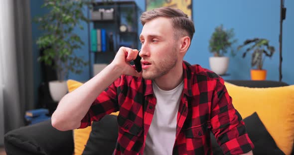 A Male Student in Flannel Shirt is Talking to His Girlfriend on the Phone While