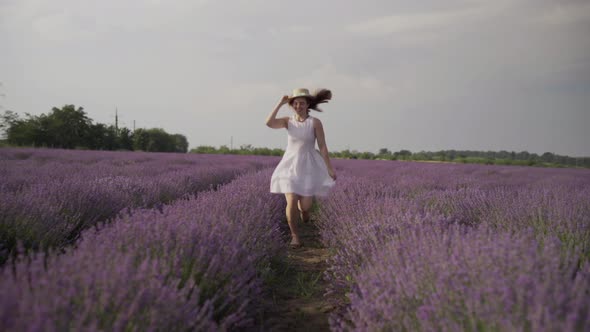 Cheerful Girl Running Along the Lavender Field in the Summer at Sunset