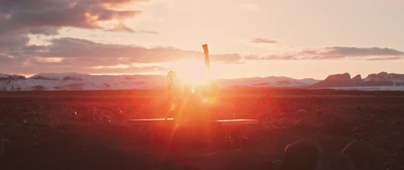 Man with camera lays down in field during sunset