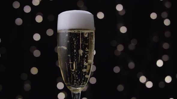 Champagne Pours Out White Foam Through the Edges of the Glass. Bokeh Background