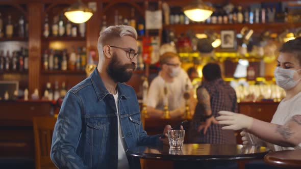 Bearded Man Texting on Smartphone Sitting at Modern Pub