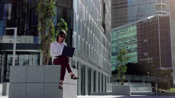 Focused businesswoman working on laptop computer in business district. 