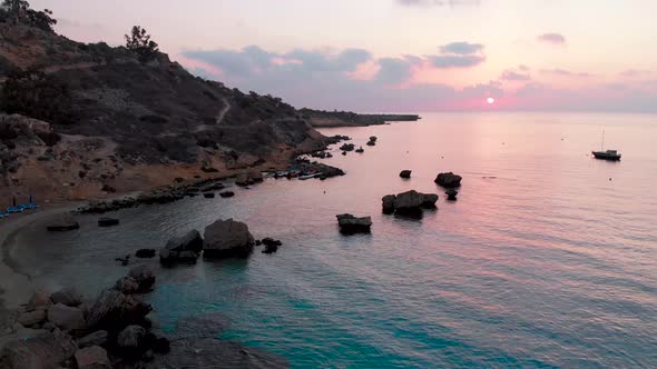 Aerial rising shot from the beach to the sky over Konnos Bay at sunset