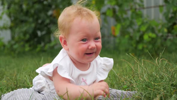 Blue eyed girl smiling outdoor. Toddler playing in the garden. Active baby on green grass.