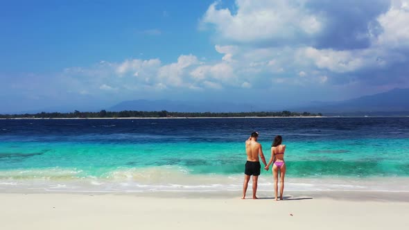 Romantic couple happy together on tropical bay beach wildlife by blue lagoon with white sand backgro