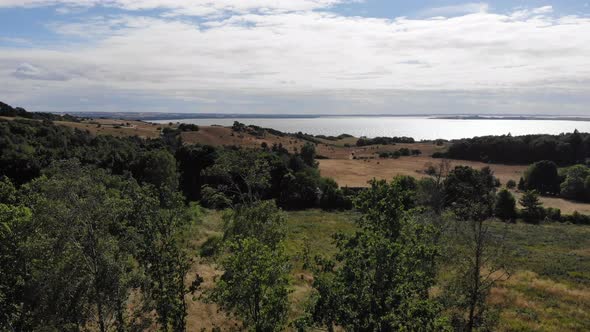 Aerial view of the coastline of Sejerøbugten with hills, fields and ocean.