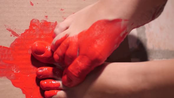 Close-up on Bare Feet of Performance Artist Painting on Cardboard with Her Feet and Red Paint | Slow