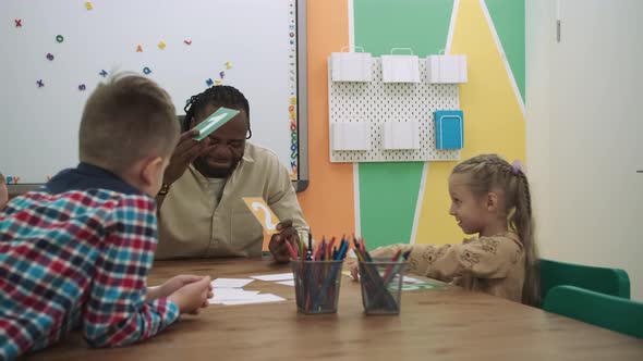 African American Teacher and a Group of Children are Learning Numbers While Sitting at the Table in