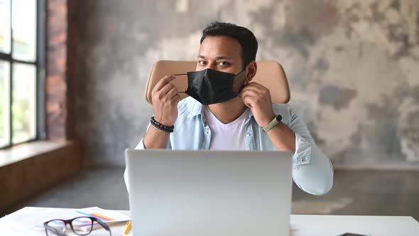 Cheerful Indian Male Office Employee Man Taking Off Medical Protective Mask