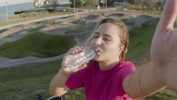 Girl Drinking Water in Skate Park and Recording Video on Phone