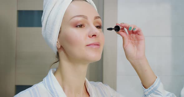 Close Up Shot of Attractive Woman Putting on Makeup with Brush Adding Mascara on Eye and Looks in