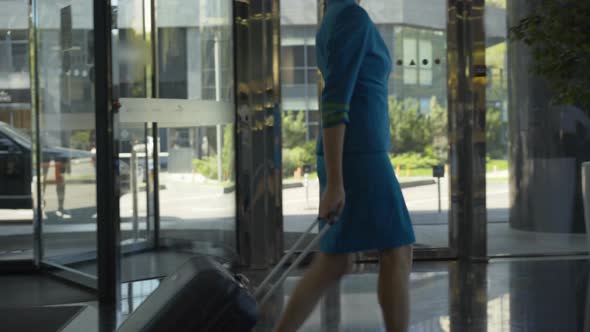 Side View of Confident Beautiful Stewardess with Suitcase Walking Along Cafeteria. Camera Follows