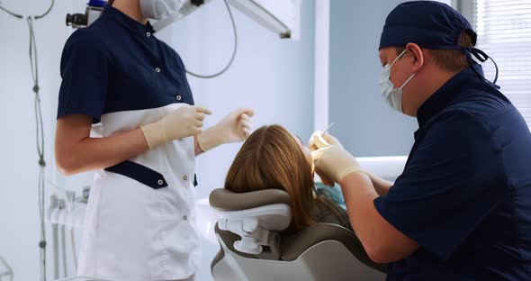 Dentist Examines a Female Patient Using a Dental Mirror