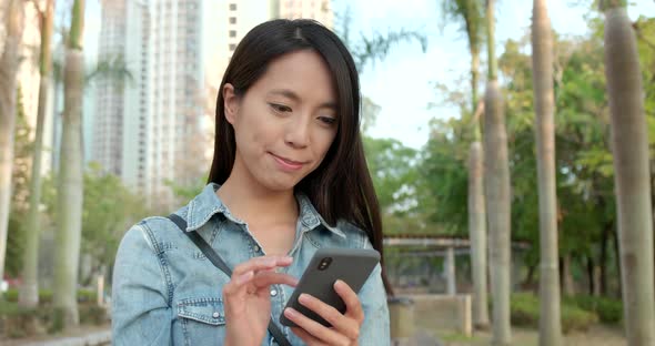 Young Woman reading on smart phone at outdoor park