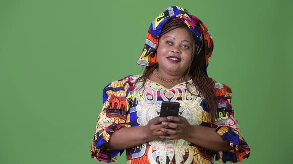 Overweight Beautiful African Woman Wearing Traditional Clothing Against Green Background