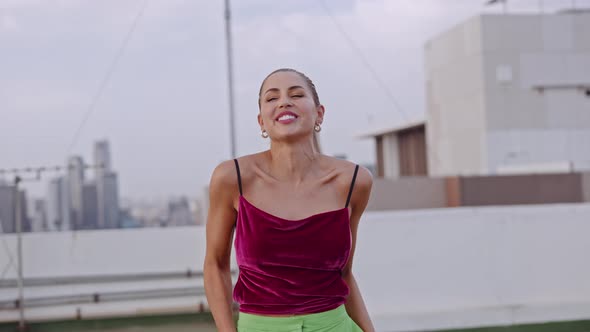 Young Woman Spinning And Laughing In Clubwear On City Rooftop