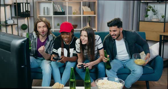 Girls Celebrating Victory in Videogames at Home Together with Male Friends which Watching the Game