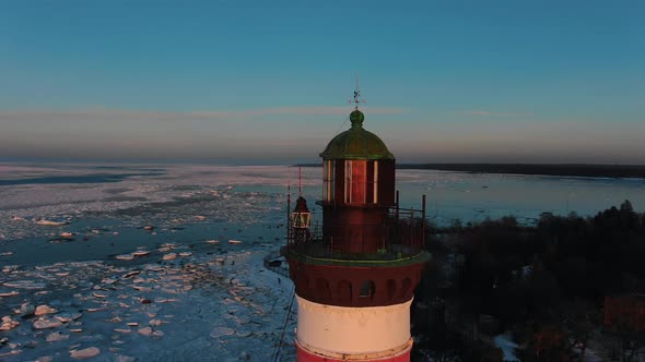 Top of Lighthouse Surrounded By Frozen Sea at Sunset