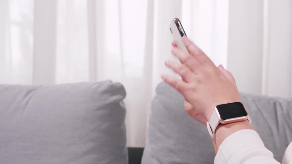 Close up of hand woman using smartphone and smartwatch in the living room for business and shopping