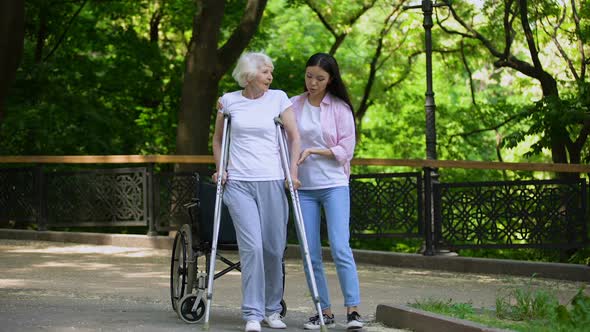 Young Woman Helping Old Lady Walking on Crutches, Hip Fracture Rehabilitation