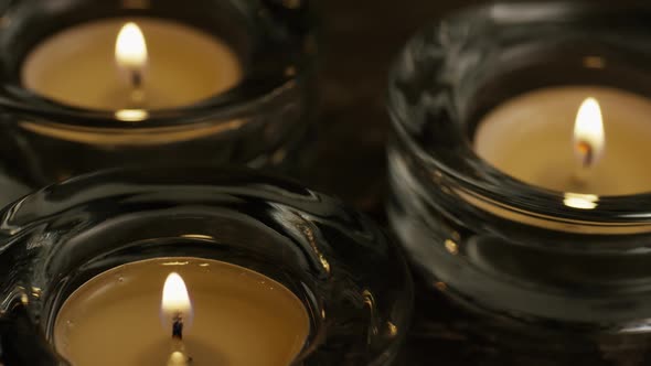 Tea candles with flaming wicks on a wooden background - CANDLES 018