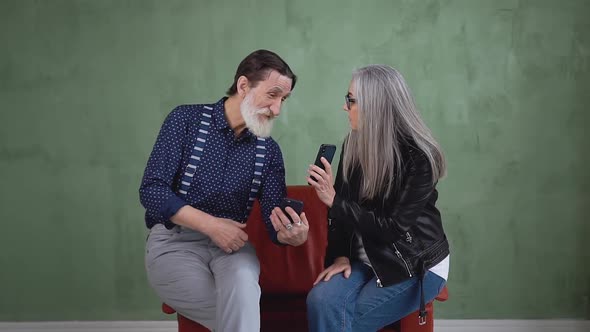 Senior Couple Sitting on Soft Chair and Talking about their Phones