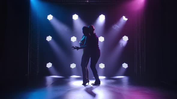 Young Couple Dancing Latin Music. Bachata, Merengue, Salsa. Shot in a Dark Studio with Neon Lights