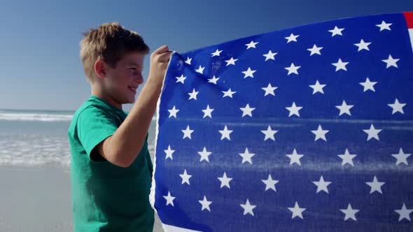 Siblings holding American flag at beach