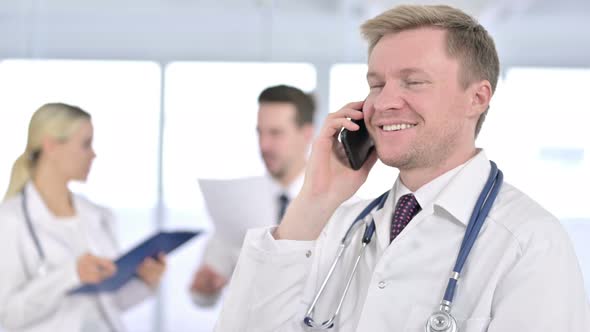 Portrait of Serious Male Doctor Talking on Smartphone 