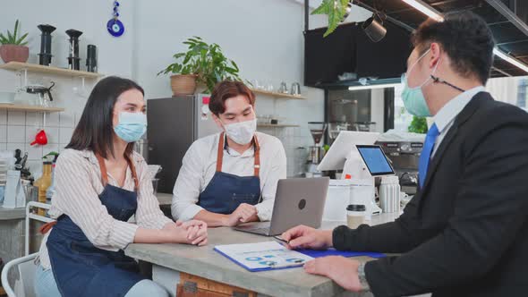 Asian business coffee shop owner couple wear face mask, consult with banker about finance payment.