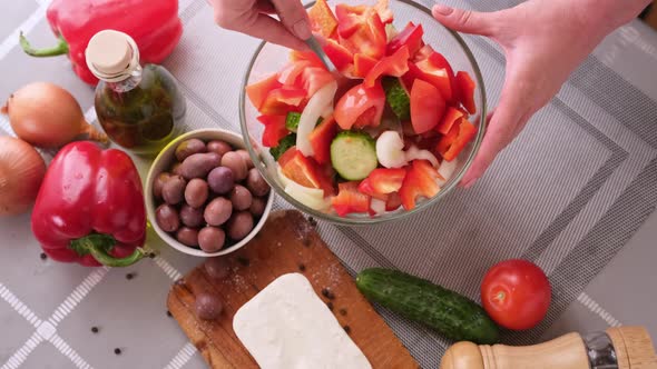 Greek Salad Preparation Series Concept  Woman Mixing Chopped Vegetables in a Glass Bowl