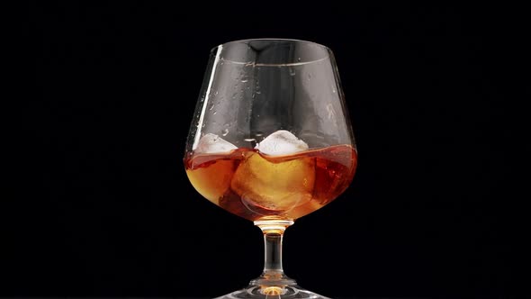 an Ice Cube Falls Into a Glass of Brandy Whiskey or Cognac Alcoholic Drinks