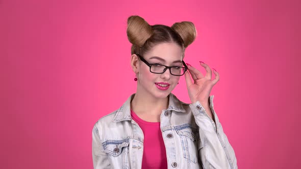 Teenager in Glasses Flirts with a Guy. Pink Background. Slow Motion