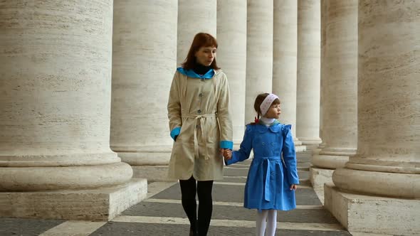 Woman with her daughter walking between columns on Piazza San Pietro, Vatican