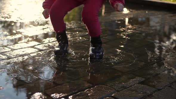 Legs in Rubber Boots Jump Through the Puddles Spray Scatterslow Motion