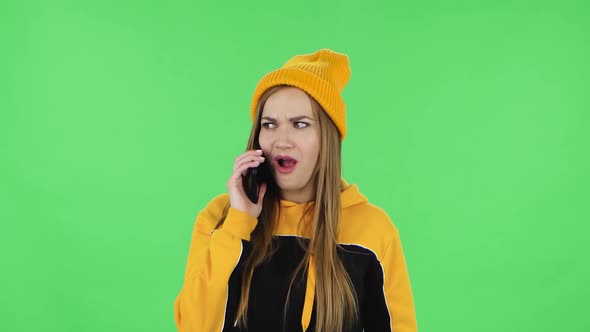 Portrait of Modern Girl in Yellow Hat Is Talking for Mobile Phone. Green Screen