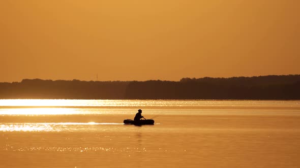 Old fisherman in a boat on orange background of sunset