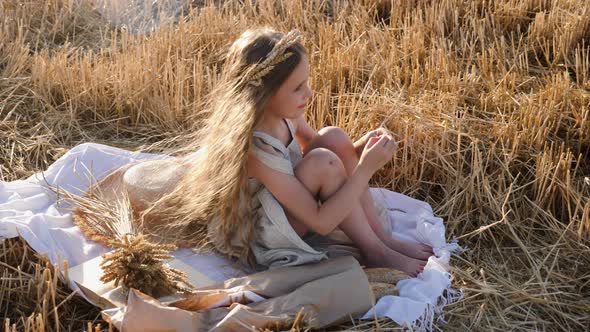 Serious Sad Girl a Child Sit on a Wheat Mown Field