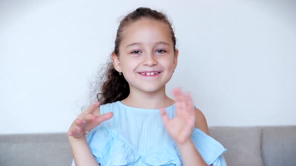 Portrait of a Funny Little Girl Smiling. Chill, Looking at the Camera, Waving Hands. Hello As a