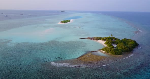 Wide angle drone clean view of a sunshine white sandy paradise beach and blue sea background in colo