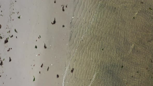 A top down shot over a beach on a sunny day.  The drone camerae forward while looking straight down