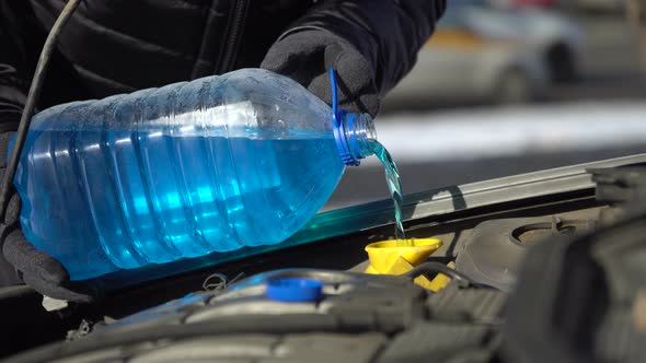 Filling Up a Windshield Washer Tank of a Car By Antifreeze Close Up