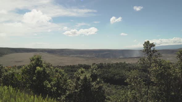 Pan of a volcano crater from left to right from up high with steam and smoke rising out of the groun