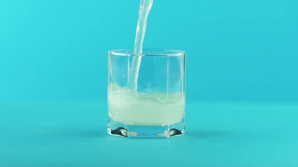 Fruit Fizzy Lemonade Soda Cold Beverage Drink Pooring Into Low Glass with Facets Blue 