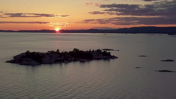 High View of Rocky Pine Tree Island in Blue Lake at Sunset, Drone Aerial Wide Dolly In. Colorful Clo