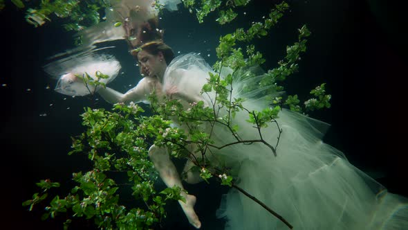 Pretty Woman in Dress is Diving in Fabulous Depth of Magical Sea with Underwater Garden