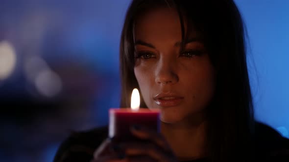 Closeup Portrait of a Darkhaired Woman Sitting and Holding an Aromatic Relaxing Candle Closing Her